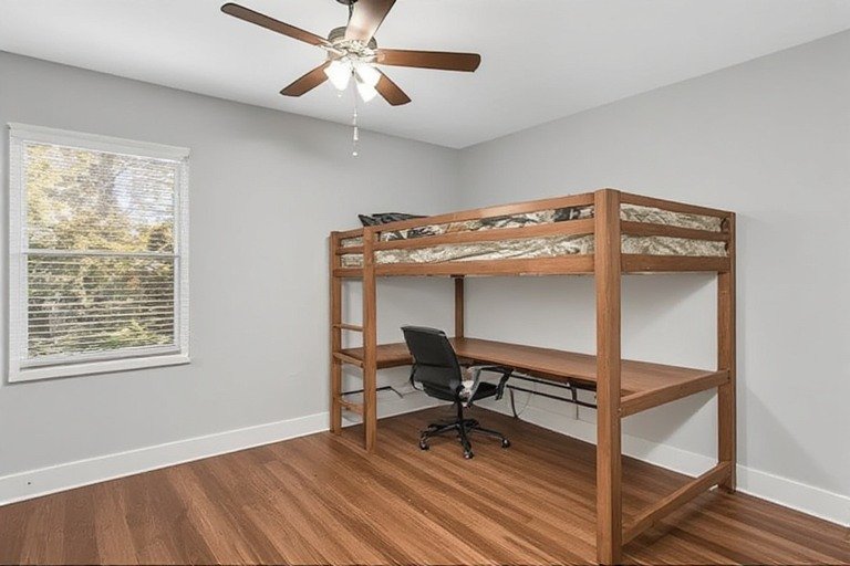 Full small bedroom with elevated loft bed and workspace underneath