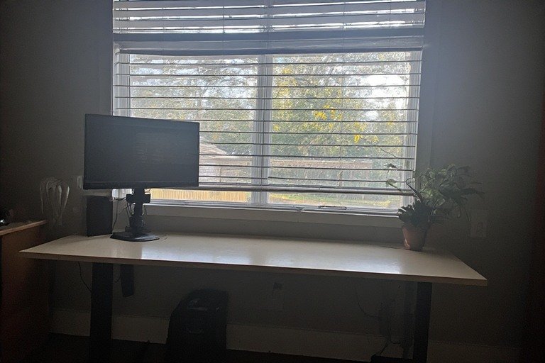 Gaming desk setup with natural light from window and adjustable positioning