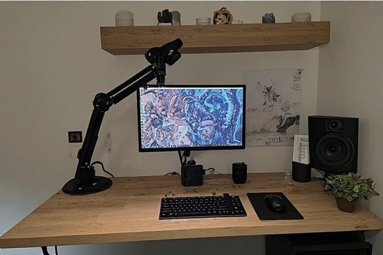Small aesthetic desk setup with monitor arm and floating shelf above
